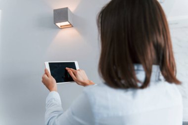 Dijital tablet ellerinde. Genç bayan gündüz vakti akıllı ev odasında..