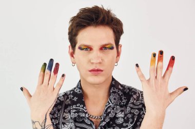 Genç eşcinsel adam stüdyoda duruyor ve kameraya poz veriyor. Hareketler ve yüz ifadeleri..