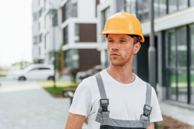 Açık havada yürüyorum. Gündüz vakti inşaatta üniformalı genç bir adam çalışıyor..
