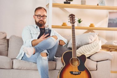 Kanepede oturuyordum. Gündelik giysiler içinde ve akustik gitarlı bir adam içeride..