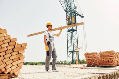 Tahta kalasla. Üniformalı genç inşaat işçisi tamamlanmamış binada meşgul..