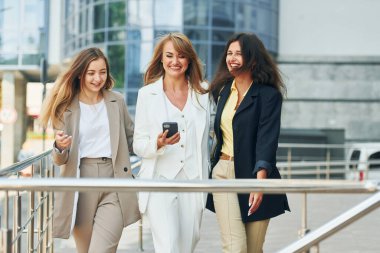 Telefonla. Resmi kıyafetli kadınlar şehirde birlikte geziyorlar..