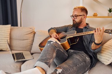 Pratik yaparken iyi vakit geçiriyorum. Gündelik giysiler içinde ve akustik gitarlı bir adam içeride..