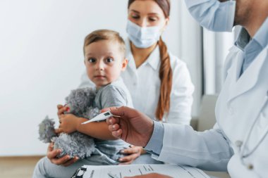 İncelenen küçük çocukla. Beyaz önlüklü iki doktor klinikte birlikte çalışıyorlar..