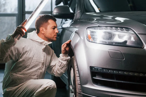 Process of painting the car. Man in uniform is working in the auto service.