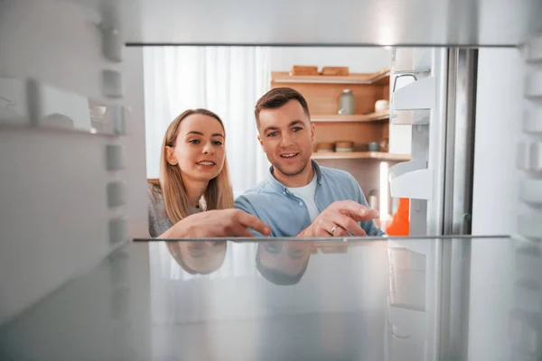 Empty fridge. Couple preparing food at home on the modern kitchen.