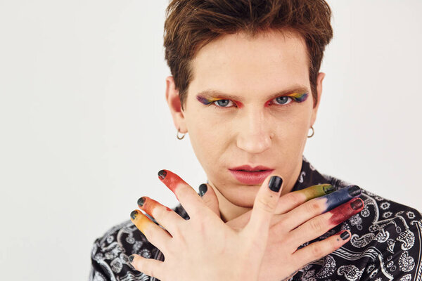 Young gay man is standing in the studio and posing for a camera. Gesturing and doing facial expressions.