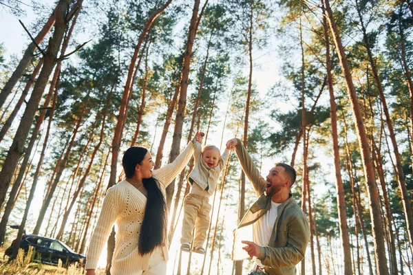 少女を手で抱える 父と母と娘の幸せな家族が森の中にいる — ストック写真