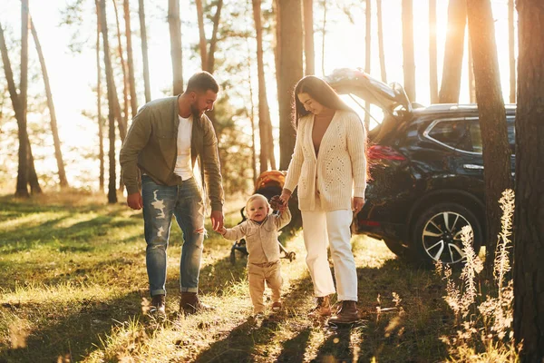 太陽の光が背景に 父と母と娘の幸せな家族が森の中にいる — ストック写真