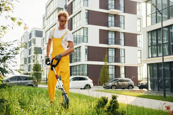 Modern buildings. Man cut the grass with lawn mover outdoors in the yard.