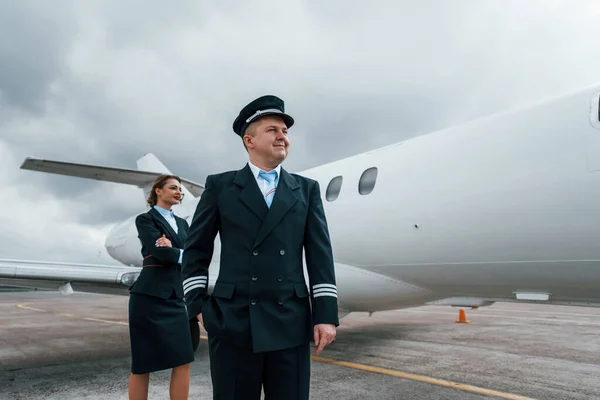 Man with woman. Aircraft crew in work uniform is together outdoors near plane.