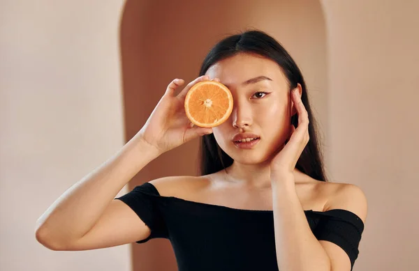 Med Bit Apelsin Ung Allvarlig Asiatisk Kvinna Som Står Inomhus — Stockfoto