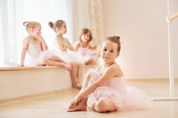 女の子は窓ガラスと床に座っています パフォーマンスの準備をしている小さなバレリーナ — ストック写真