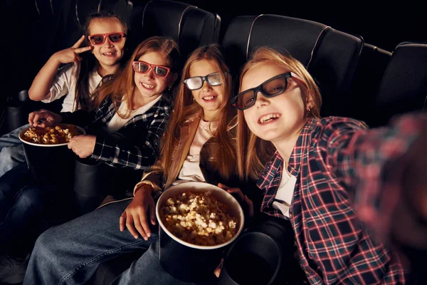 Making photo of each other. Group of kids sitting in cinema and watching movie together.