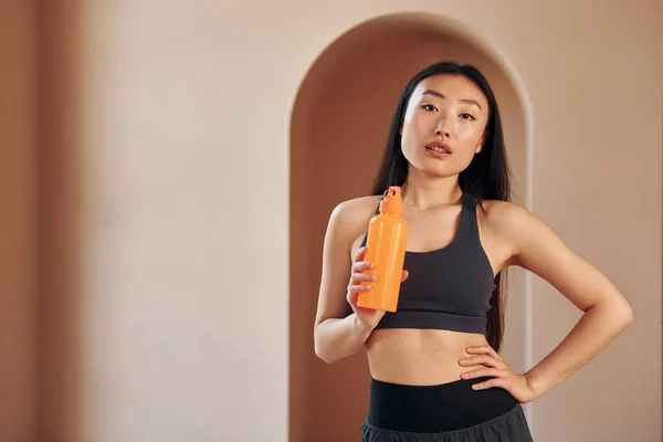 Con Bottiglia Colore Arancione Giovane Serio Asiatico Donna Standing Indoor — Foto Stock