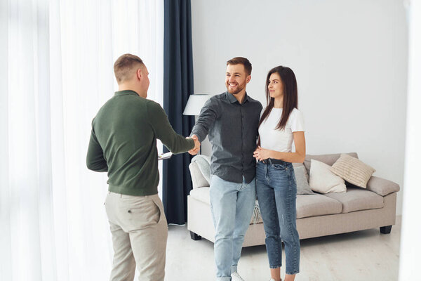 Salesman helps young couple in choosing an apartment. Conception of business and rent.