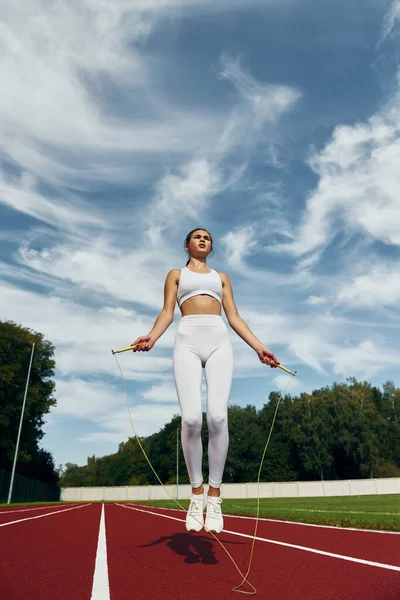 スポーツ服の若い女性が屋外でジャンプしている — ストック写真