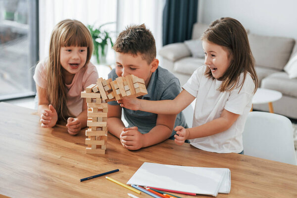 Building a tower. Playing game. Kids having fun in the domestic room at daytime together.