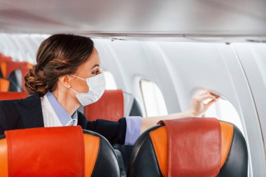 Maskeli. Yolcu uçağında çalışan genç hostes..