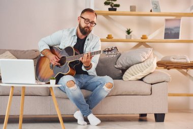 Kanepede oturuyordum. Gündelik giysiler içinde ve akustik gitarlı bir adam içeride..