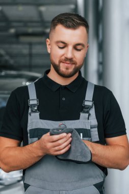 Elleri temizliyorum. Üniformalı adam gündüz vakti otosalonda çalışıyor..