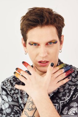 Genç eşcinsel adam stüdyoda duruyor ve kameraya poz veriyor. Hareketler ve yüz ifadeleri..