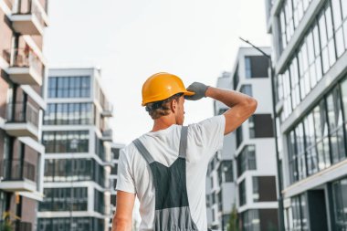 İş raporları. Gündüz vakti inşaatta üniformalı genç bir adam..