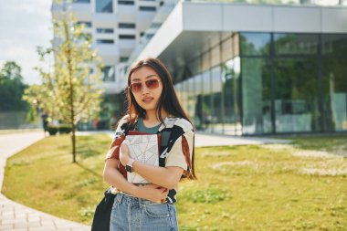 Elinde not defteriyle. Genç Asyalı kadın gündüz vakti dışarıda..