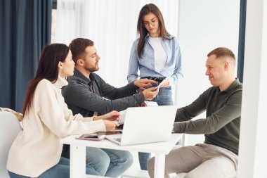 Bir grup insan masada oturarak ofiste çalışıyor..