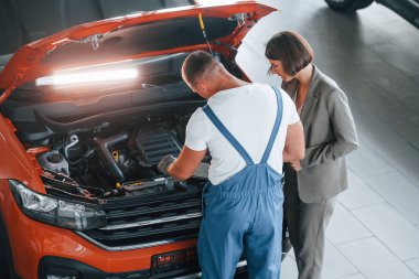 Şık giyinmiş bir kadın. Kadın arabasının tamircisi bir adam. Profesyonel hizmet..