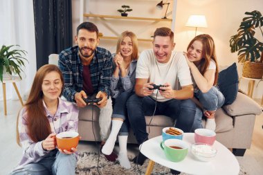 Oyun oynamak için joystickleri kullanmak. Bir grup arkadaş içeride parti veriyor..