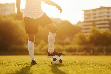 Güzel güneş ışığı. Genç futbolcu spor sahasında antrenman yapıyor..