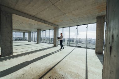 Güzel güneş ışığı büyük pencereden içeri girer. Resmi kıyafetli genç adam içeride inşaatta çalışıyor..