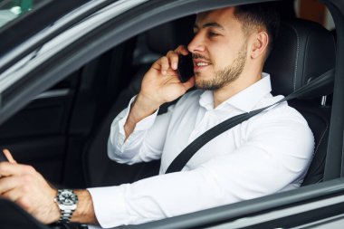 Başarılı bir adam. Beyaz gömlekli genç adam modern bir otomobilin içinde oturuyor..