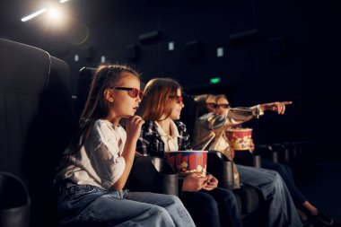 Patlamış mısırla. Bir grup çocuk sinemada oturup birlikte film izliyorlar..