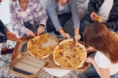 Lezzetli pizza yiyorum. Bir grup arkadaş içeride parti veriyor..