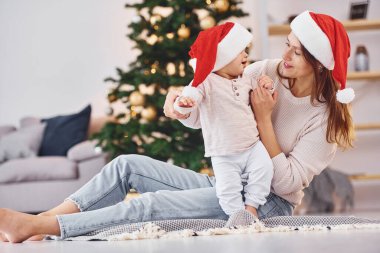Noel Baba şapkalarıyla. Anne ve küçük kızı evde birlikte..