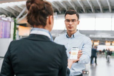 Adam aşı sertifikası gösteriyor. Resmi kıyafetli genç işadamı gündüz vakti havaalanında..