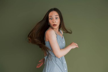 Stüdyoda duran, sıradan giyinmiş, korkmuş genç bir kadın..