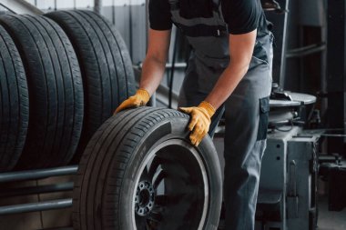 Lastikle yürüyorum. Üniformalı adam otomobil servisinde çalışıyor..