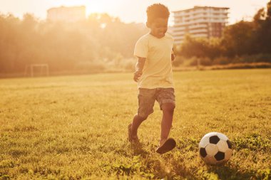 Futbol oynuyor. Afrikalı Amerikalı çocuk yaz günlerinde tarlada eğleniyor..