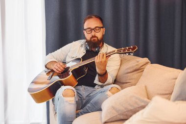Rahatlamış hissediyorum. Gündelik giysiler içinde ve akustik gitarlı bir adam içeride..