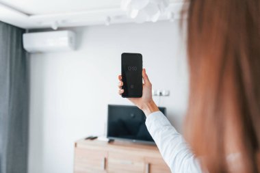 Klimayı tabletle kontrol etmek. Genç kadın, gündüz vakti modern evin içinde..