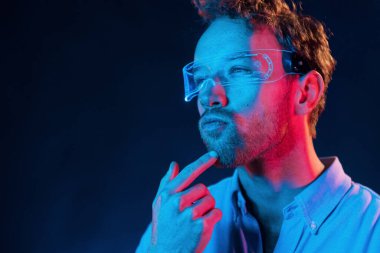 Neon ışıkları. Genç Avrupalı adam karanlık stüdyoda..