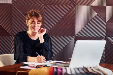 Kadın elinde laptop ve belgelerle masada oturuyor. Yeni lüks restoranın içinde..