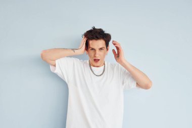 Genç eşcinsel adam stüdyoda duruyor ve kameraya poz veriyor..