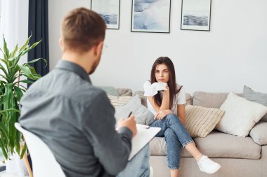 Genç bir kadın bir psikologda resepsiyonda. Kanepede oturuyor..