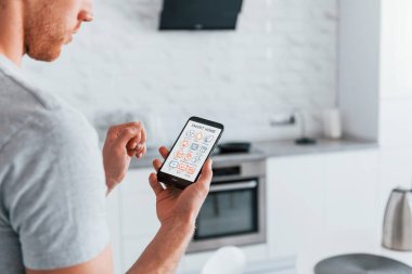 Akıllı ev teknolojisini kontrol eden yetişkin bir adamın arka görüntüsü..