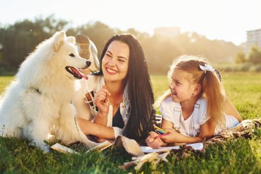 Anne ve kızı tatlı köpekleriyle çimlere uzanırken dinleniyorlar..