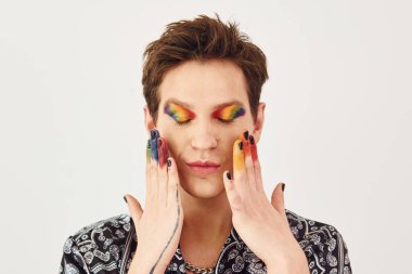 Genç eşcinsel adam stüdyoda duruyor ve kameraya poz veriyor. Hareketler ve yüz ifadeleri..